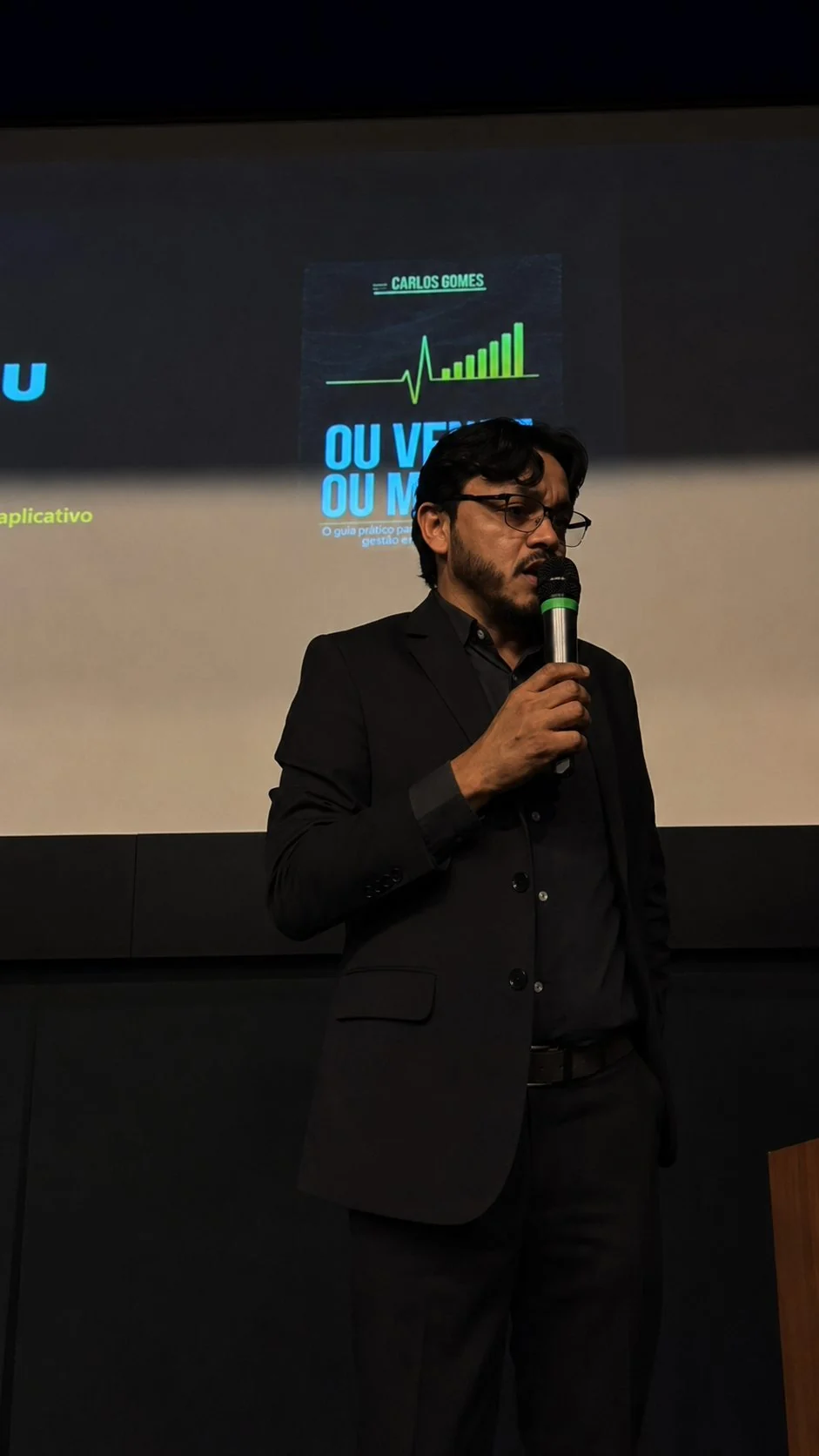 Carlos Gomes no palco com o livro Ou Vende ou Morre projetado ao fundo